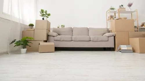 Empty living room with a sofa, moving boxes and clean floors ready for a move-out inspection