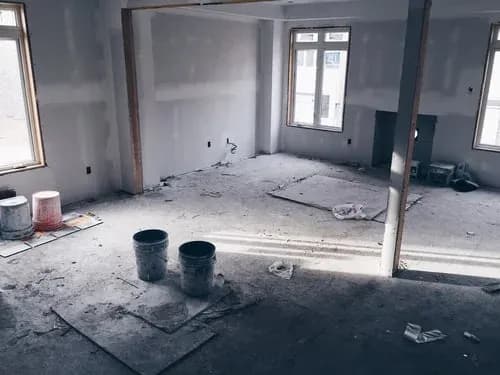 Interior under renovation with construction dust, buckets and debris before a post-construction clean