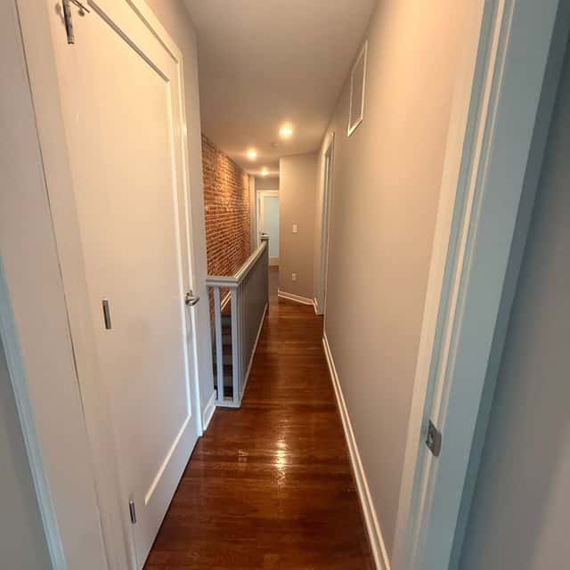 Cleaned hallway with white doors, refinished hardwood floor and an exposed brick accent wall — Perficient Deep Cleaning LLC, Philadelphia, PA
