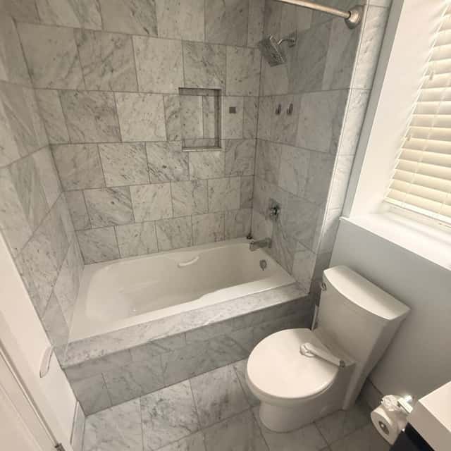 Spotless marble-tiled bathroom with a bathtub, shower niche and toilet after a deep clean — Perficient Deep Cleaning LLC, Philadelphia, PA