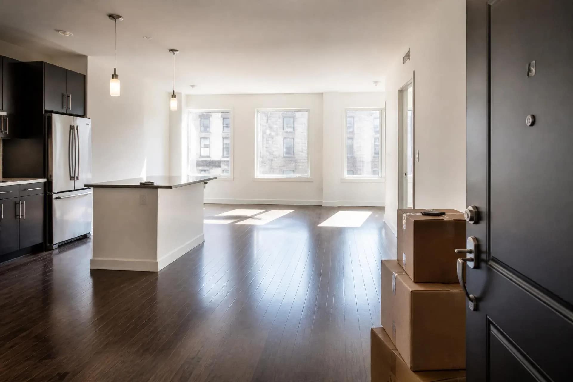 Clean empty apartment with moving boxes and a rolled rug ready for a move-out cleaning service
